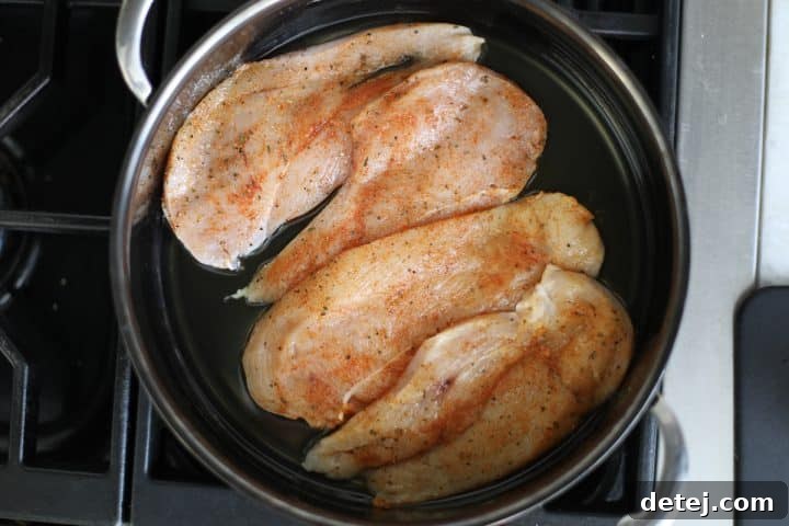 Seasoned chicken cutlets in a hot pan, beginning to sear.