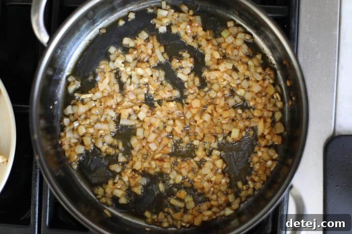Sautéed onions and minced garlic in a pan, releasing their aromas.