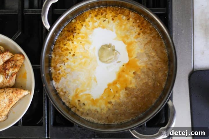 Cream, onions, garlic, and broth creating a rich sauce in the pan.