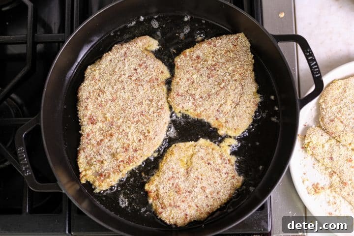 Ultimate Breakfast Chicken Cutlets 11 chicken cutlets being shallow-fried in a pan, achieving a golden-brown crust.
