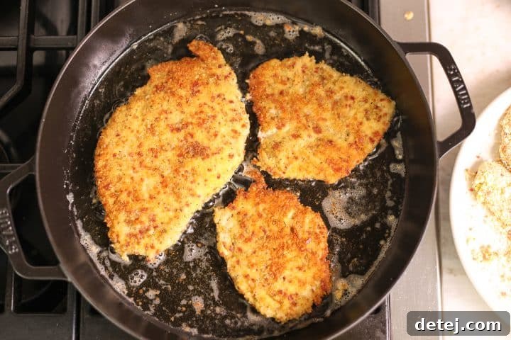 Ultimate Breakfast Chicken Cutlets 12 perfectly fried chicken cutlets resting on a cooling rack.