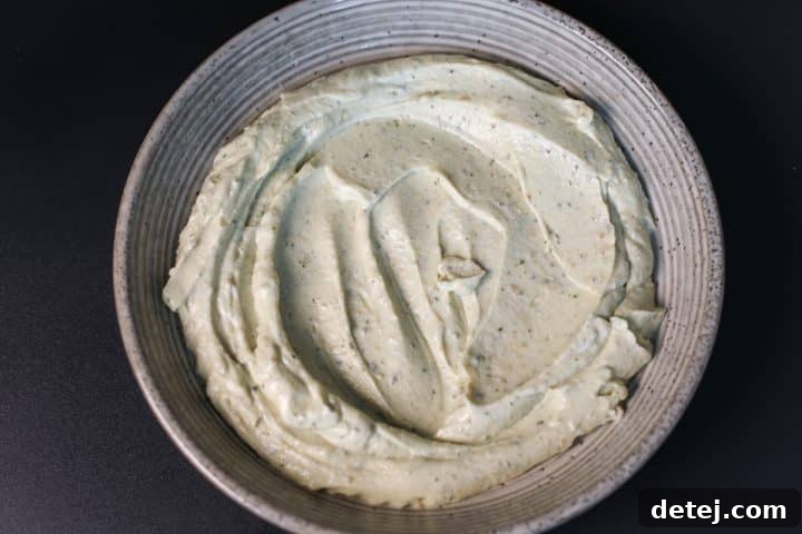 The smooth, whipped pesto ricotta spread evenly in a serving bowl.