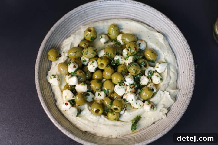 The finished appetizer, with marinated olives and mozzarella spooned over whipped pesto ricotta, ready for serving.