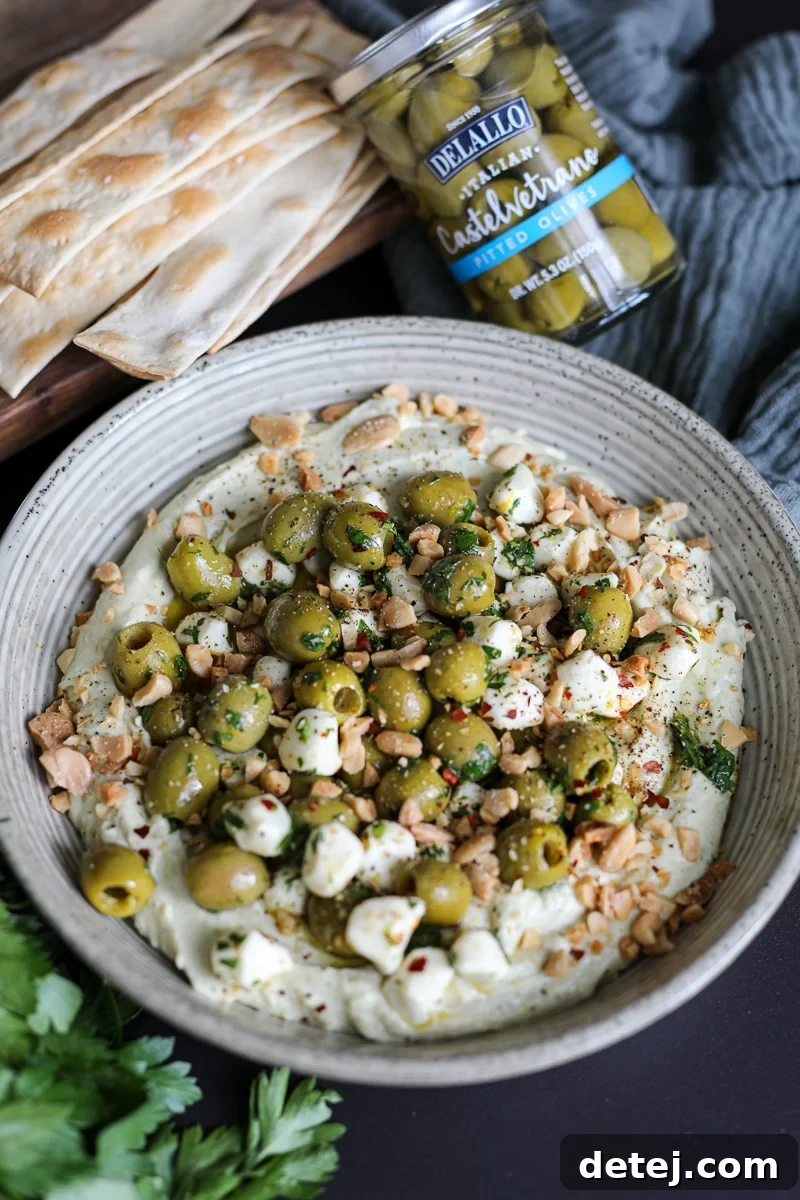 A beautifully presented olive dip on a serving platter, surrounded by crackers and fresh garnishes.