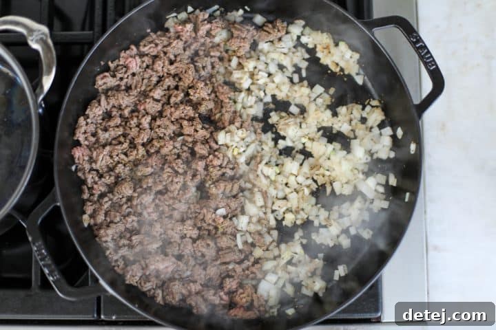 Beef and onions being sautéed in a pan, releasing savory aromas.