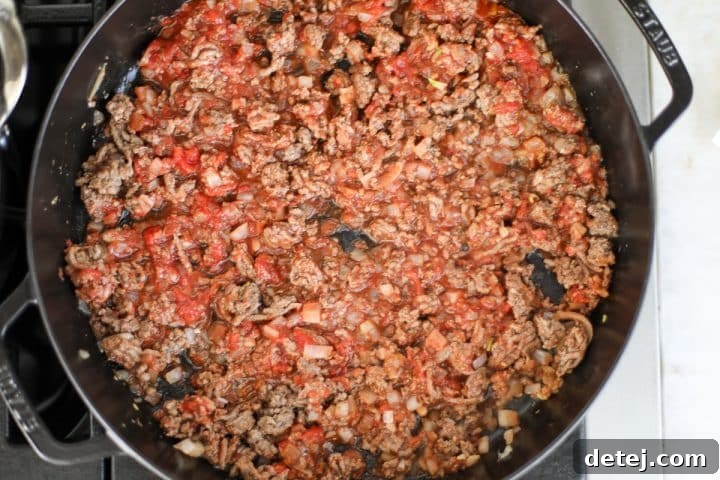 Rich beef mixture with tomato sauce simmering gently in a pan.