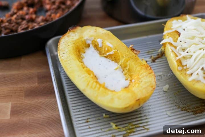 Creamy sauce being spooned into a roasted spaghetti squash.