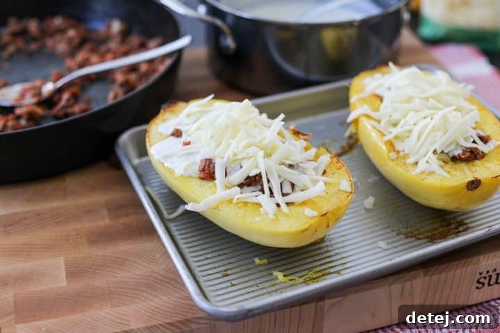Shredded mozzarella cheese generously sprinkled on top of a spaghetti squash boat, ready for broiling.