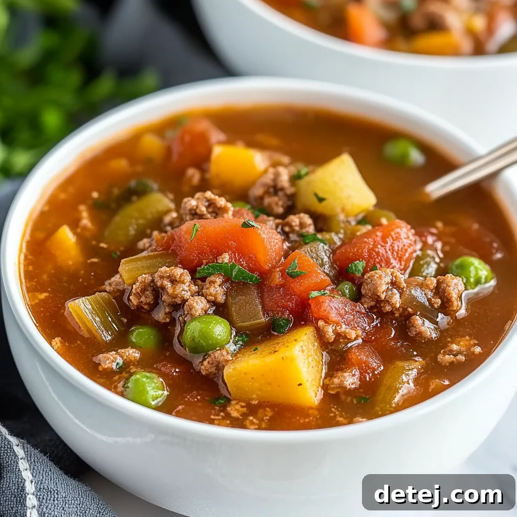 Two bowls of easy hamburger vegetable soup garnished with fresh herbs