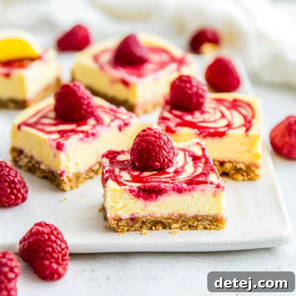 Delicious Raspberry Lemon Cheesecake Bars, perfectly sliced and ready to serve, showcasing vibrant red raspberry swirls against a creamy yellow cheesecake base on a buttery graham cracker crust.