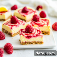 Overhead shot of Raspberry Lemon Cheesecake Bars in a baking dish, with one bar partially cut, showcasing the vibrant raspberry swirls.
