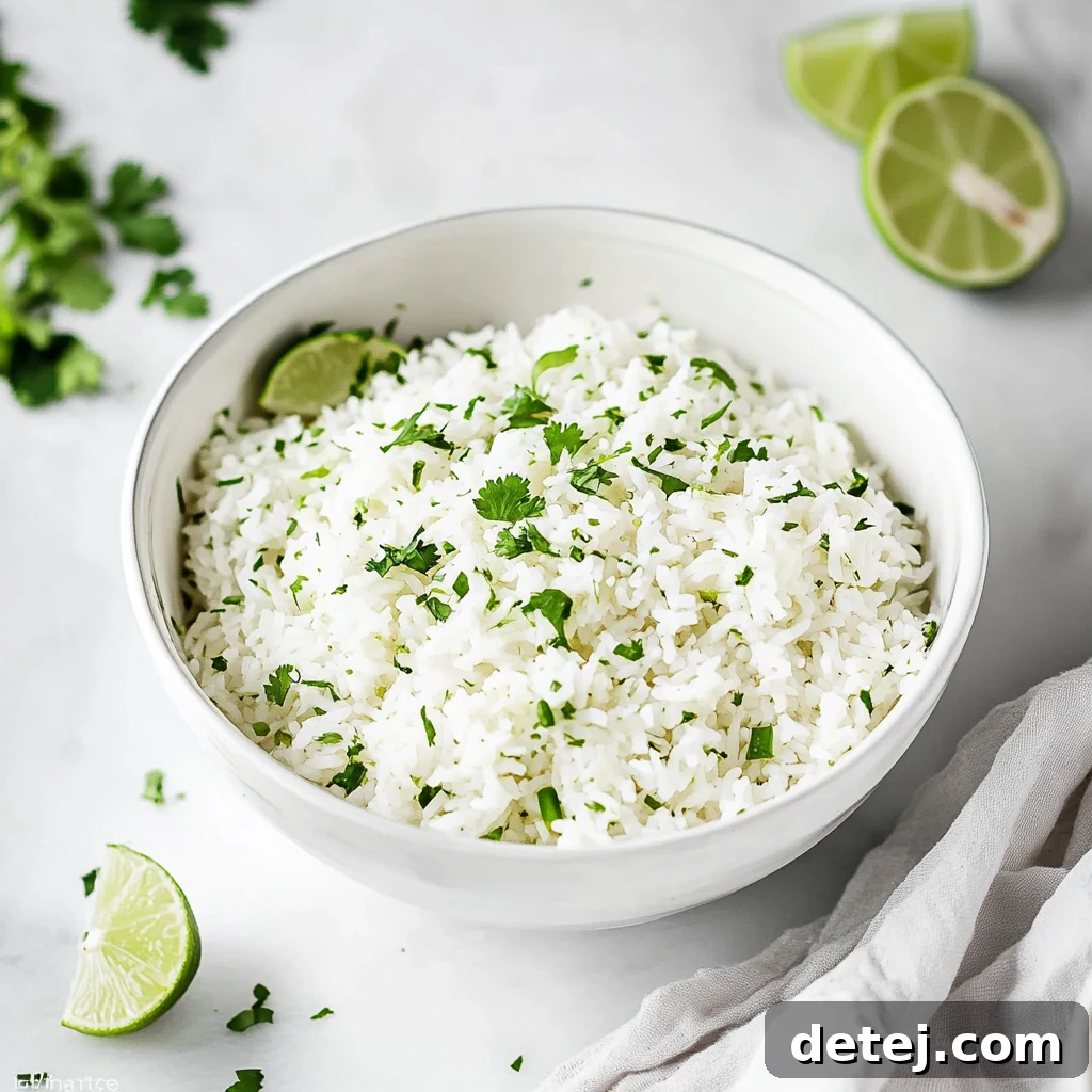 A close-up shot of freshly cooked, fluffy white rice mixed with vibrant green cilantro and lime wedges.