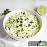 A top-down view of the Chipotle Copycat Cilantro Lime Rice in a serving bowl, garnished with fresh cilantro and lime wedges.