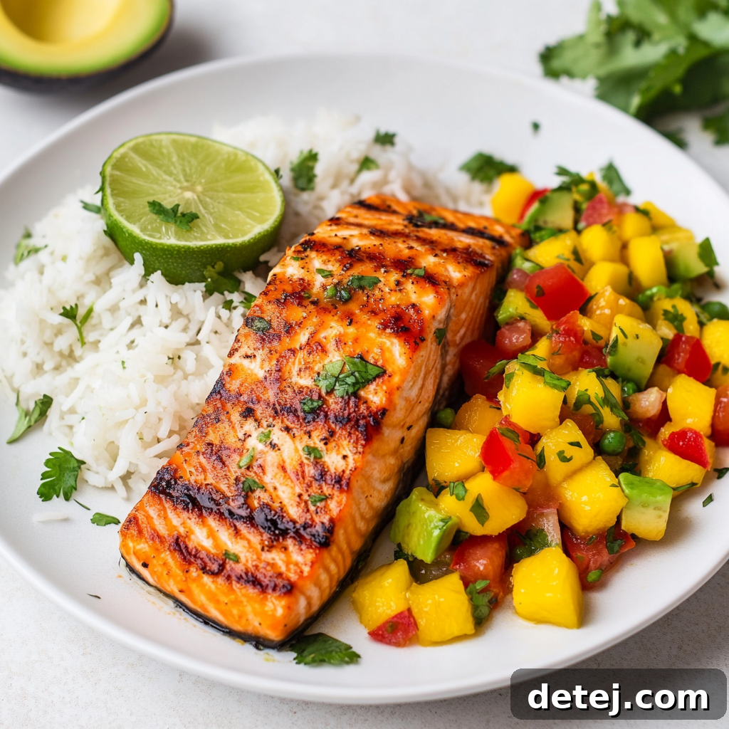 Plate with grilled salmon fillet topped with mango salsa and a side of cilantro lime rice.