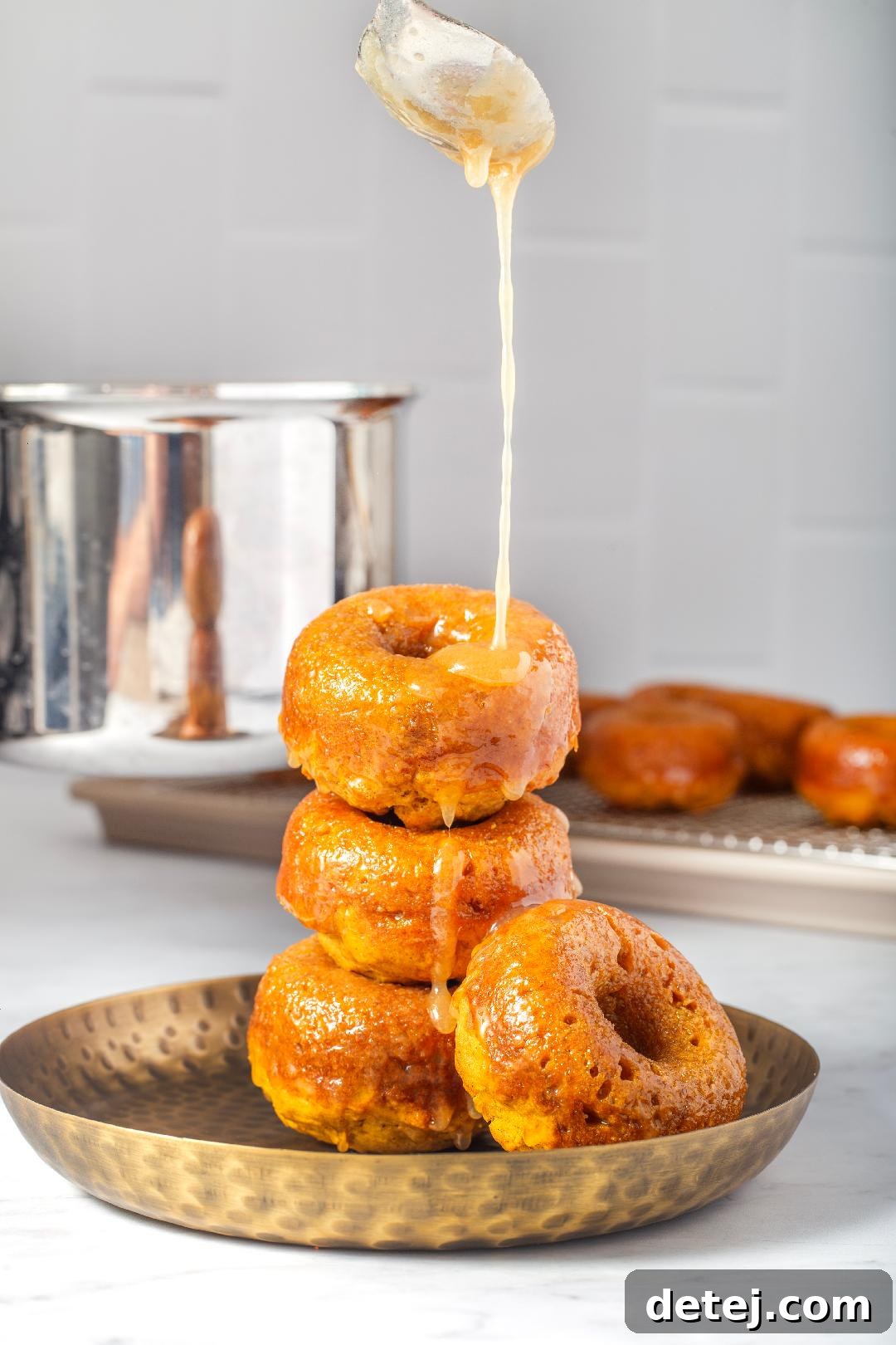 Maple glaze being drizzled over warm pumpkin donuts