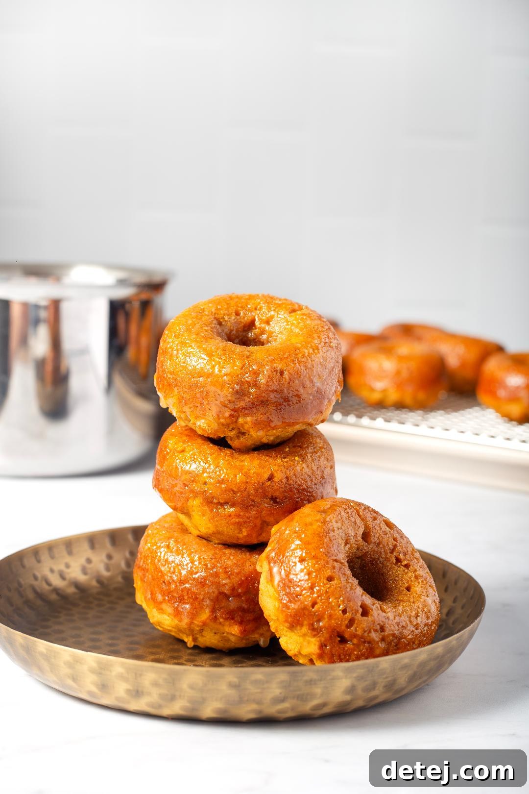 A stack of freshly glazed pumpkin donuts, invitingly presented