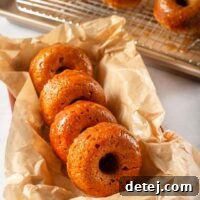 Close-up of a stack of pumpkin donuts with maple glaze, garnished with cinnamon stick