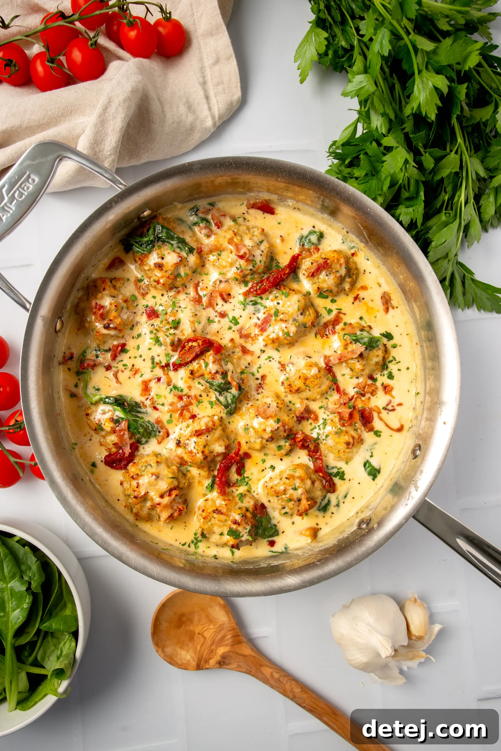 Golden-brown creamy Tuscan chicken meatballs nestled in a rich sauce with sun-dried tomatoes and spinach