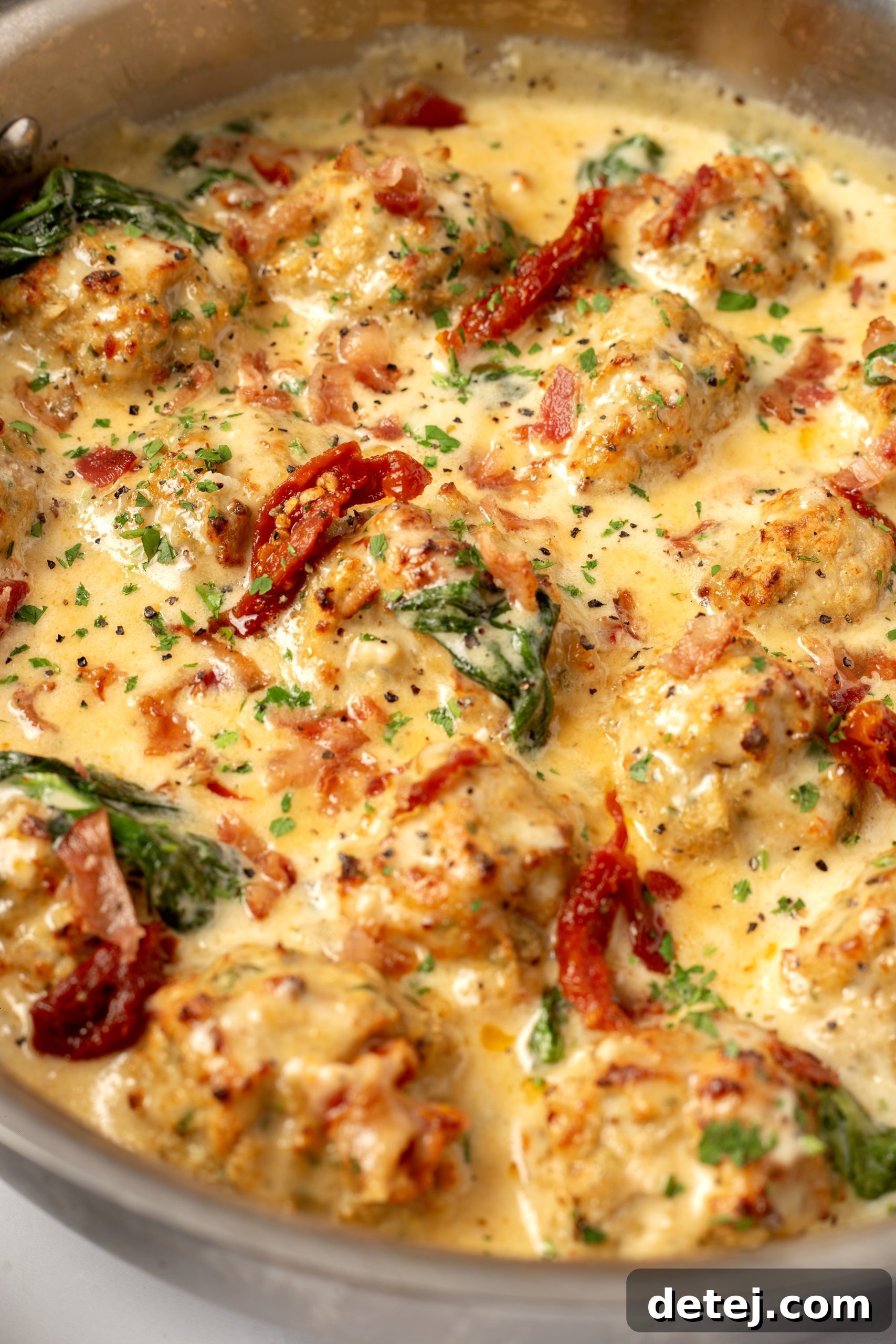 Rich, creamy Tuscan sauce simmering in a large skillet with spinach and sun-dried tomatoes