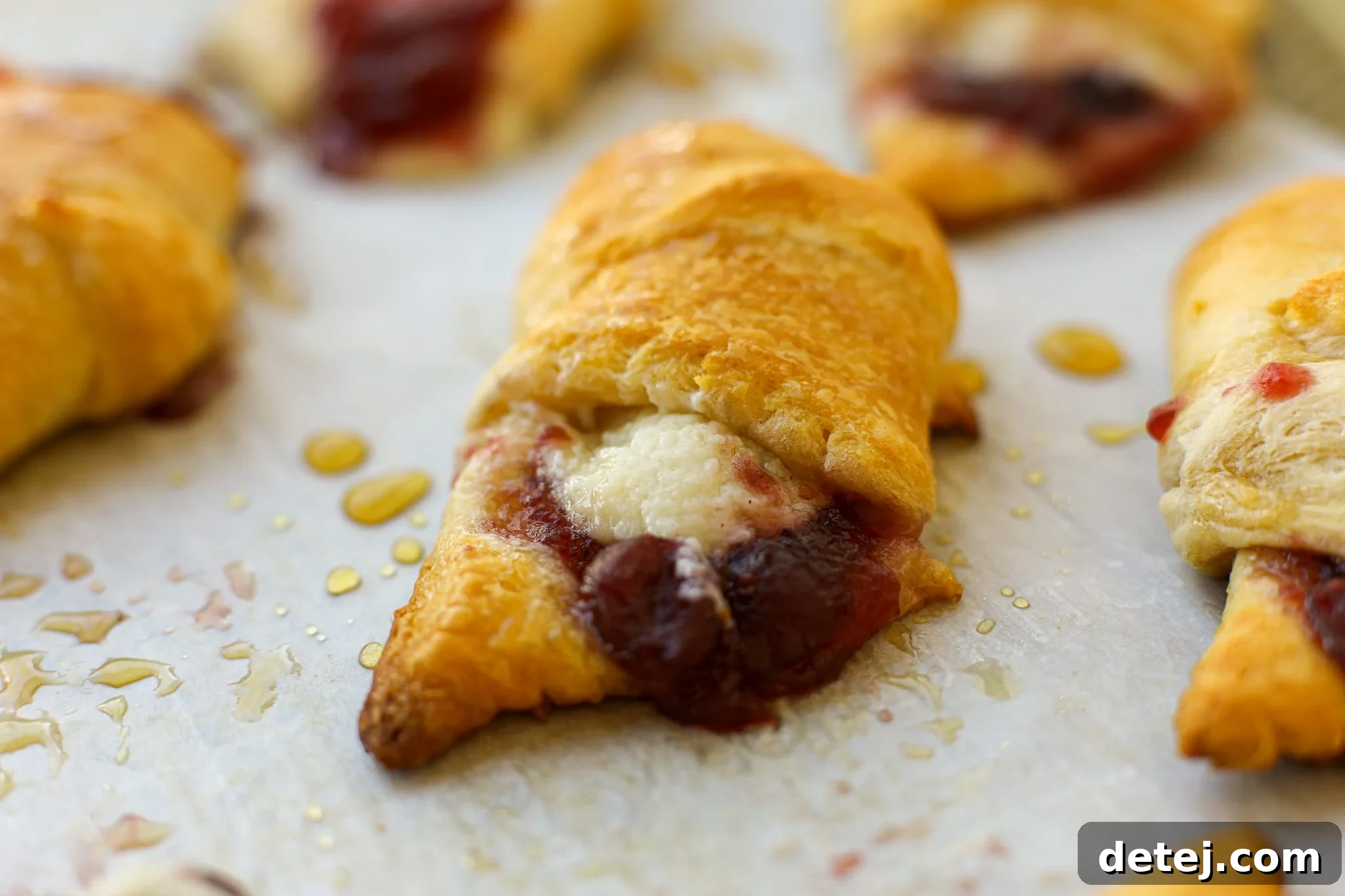 Two Cranberry Cream Cheese Roll-Ups dusted with powdered sugar, on a white plate with a fork.