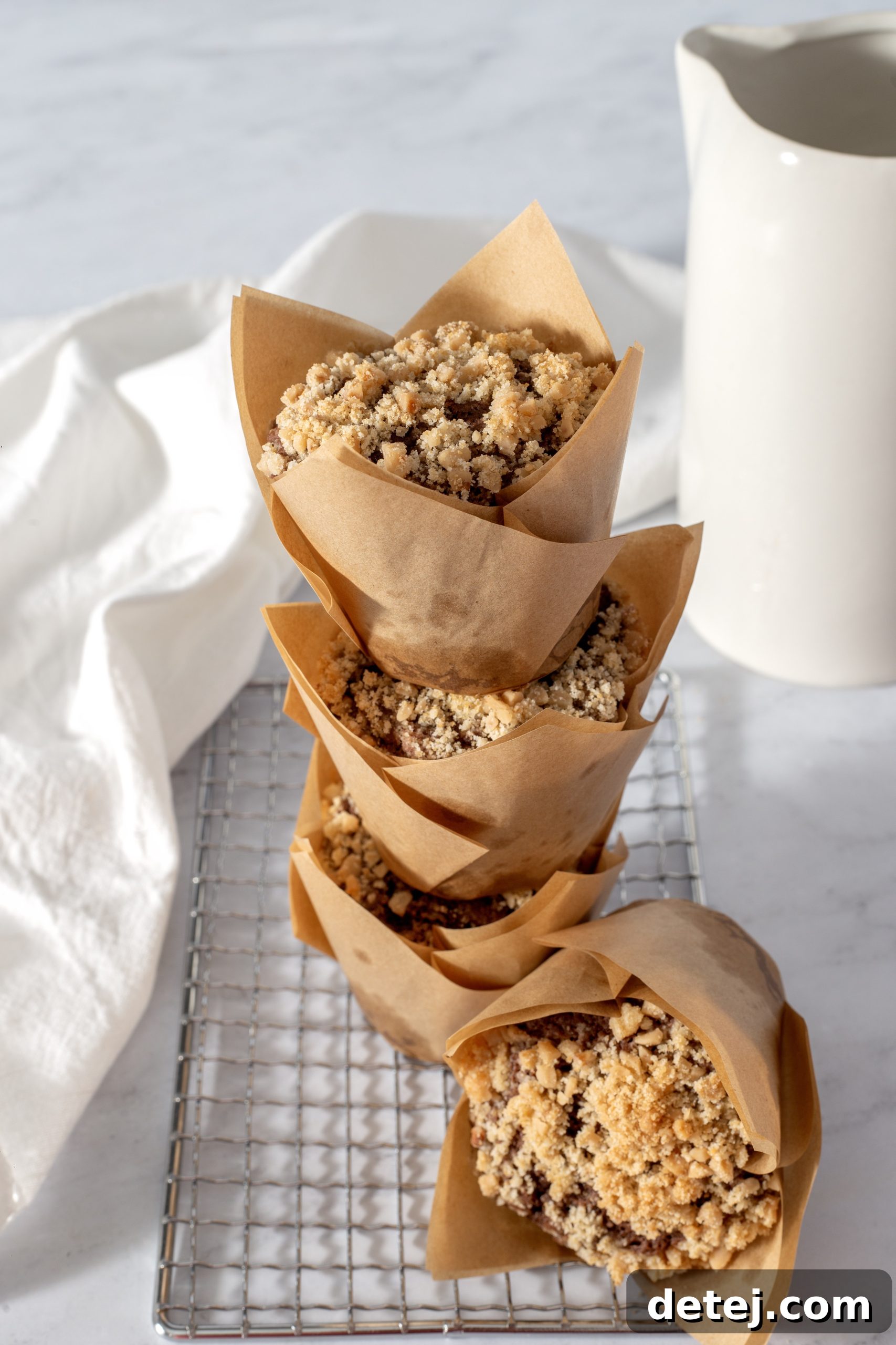 Close-up of a perfectly baked chocolate muffin, rich and dark, crowned with a shimmering toffee streusel, resting on parchment paper.