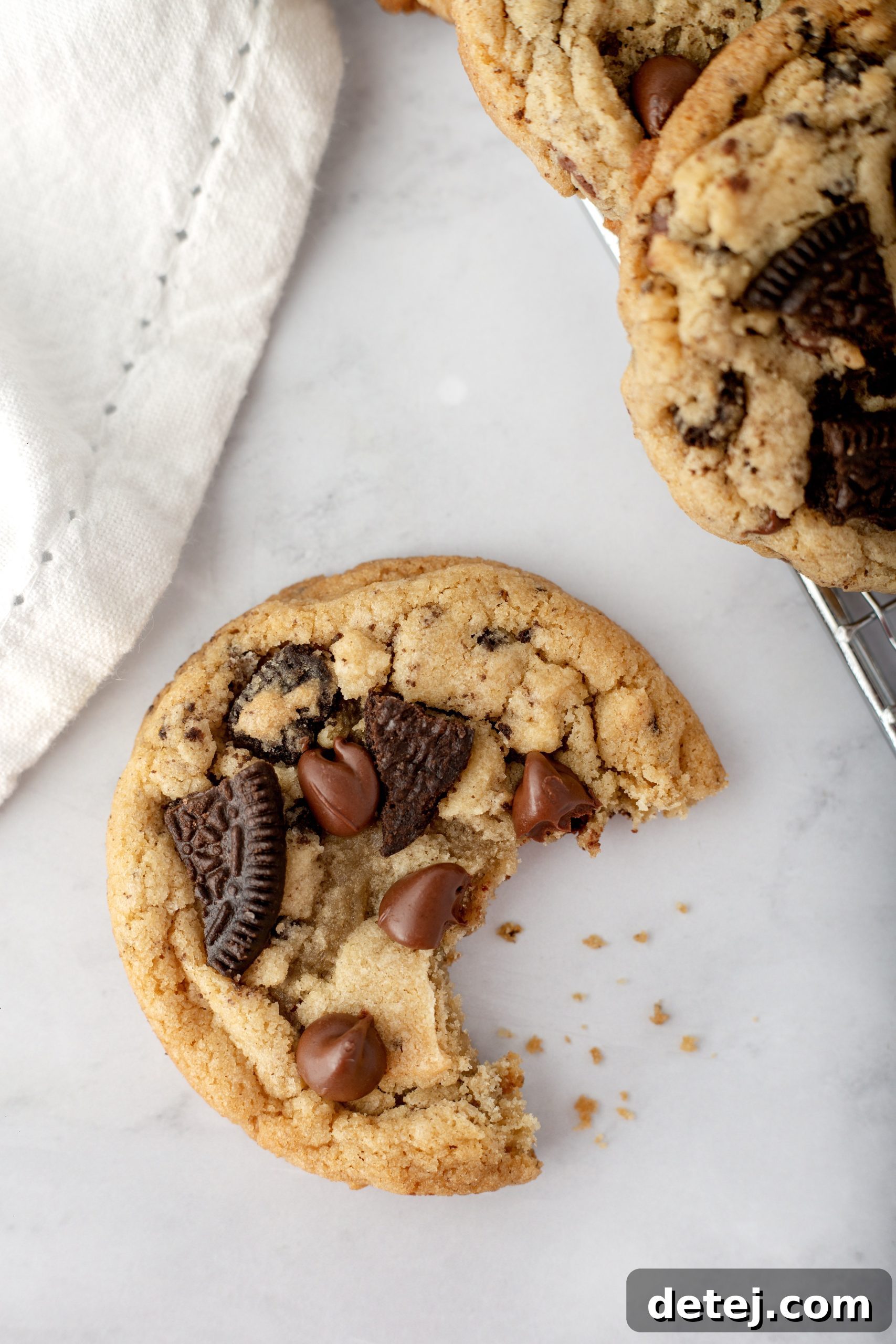 A stack of warm, bakery-style Oreo Chocolate Chip Cookies with a glass of milk, ready to be enjoyed.