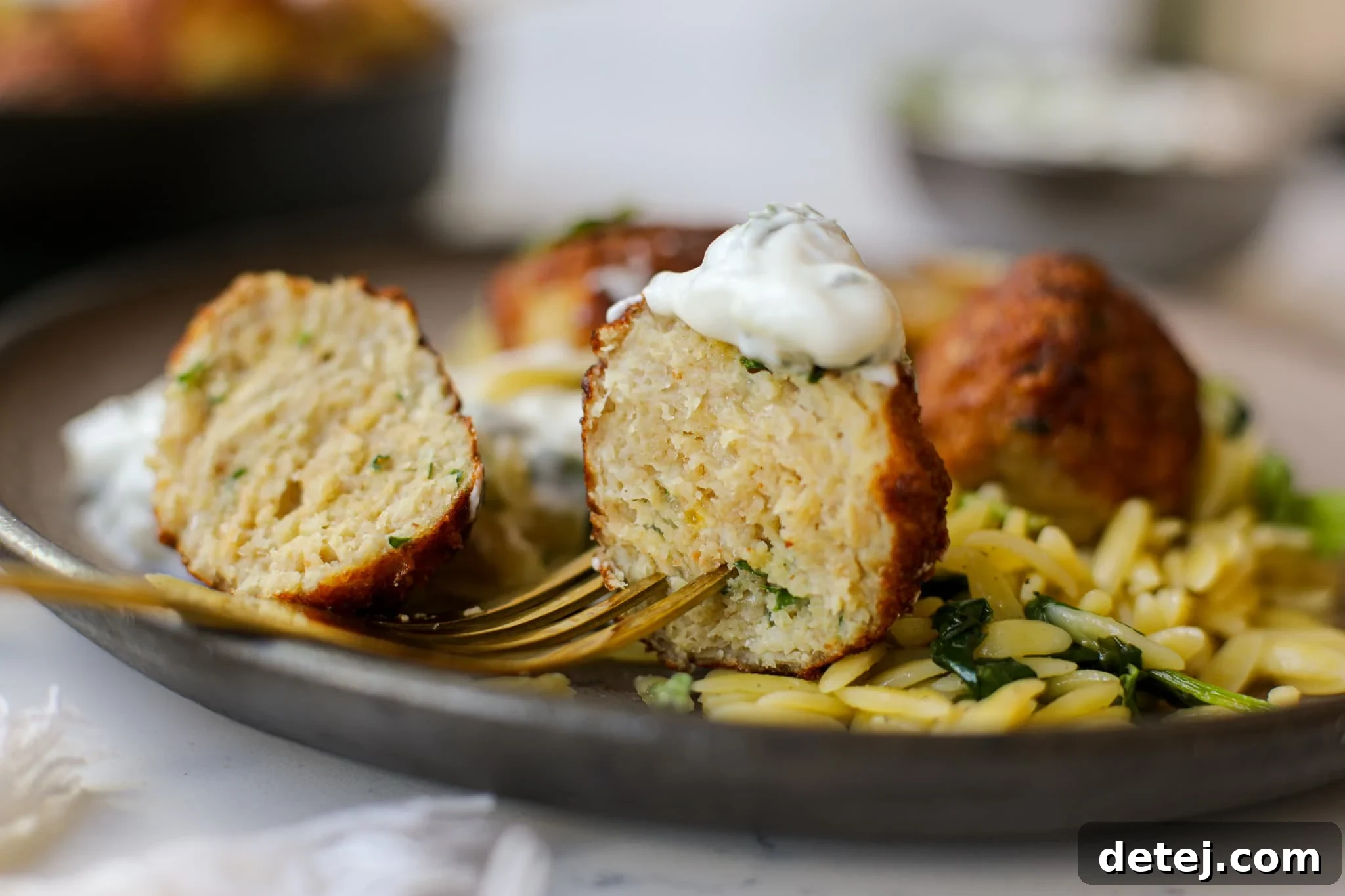 Close-up of golden-brown Greek Chicken Meatballs garnished with fresh dill.