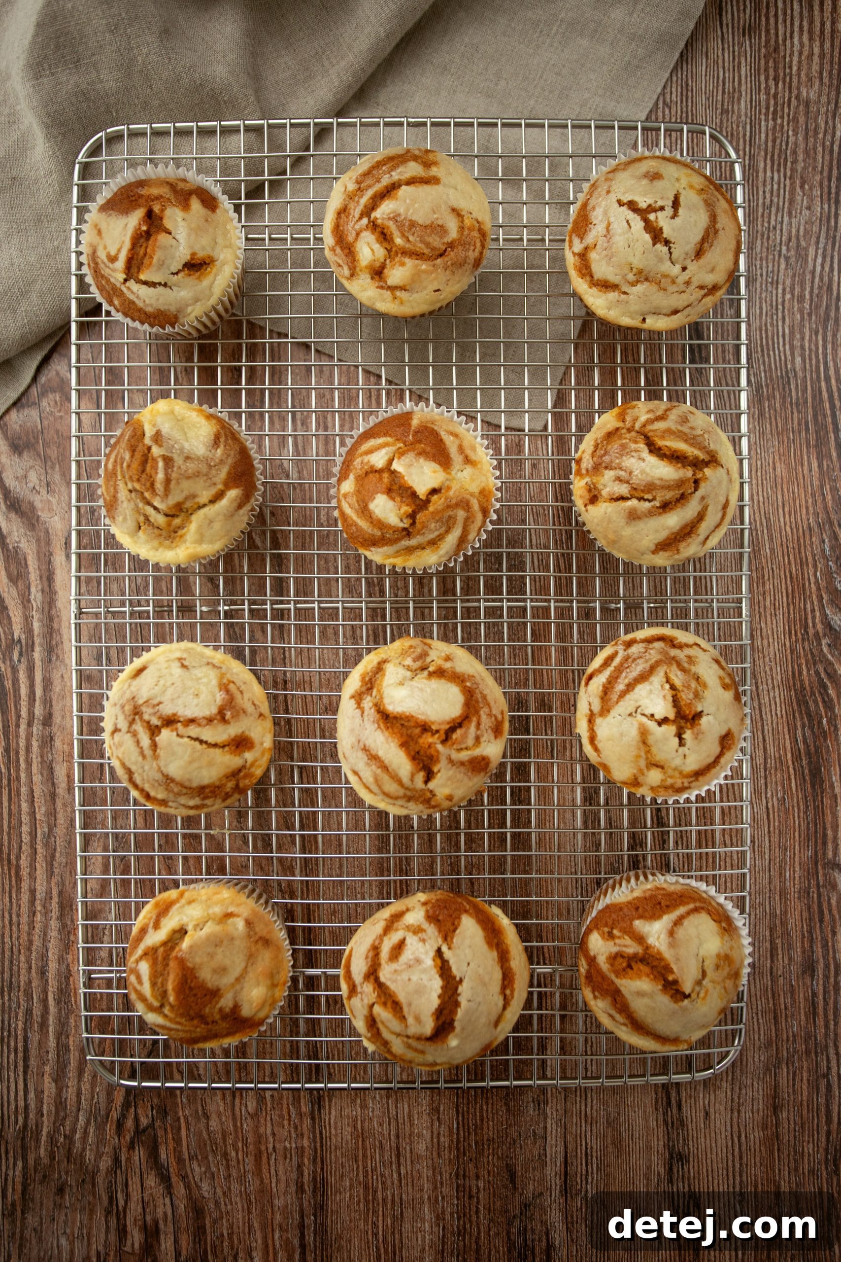 Freshly baked pumpkin cheesecake swirl muffins, golden brown with visible cream cheese swirls.