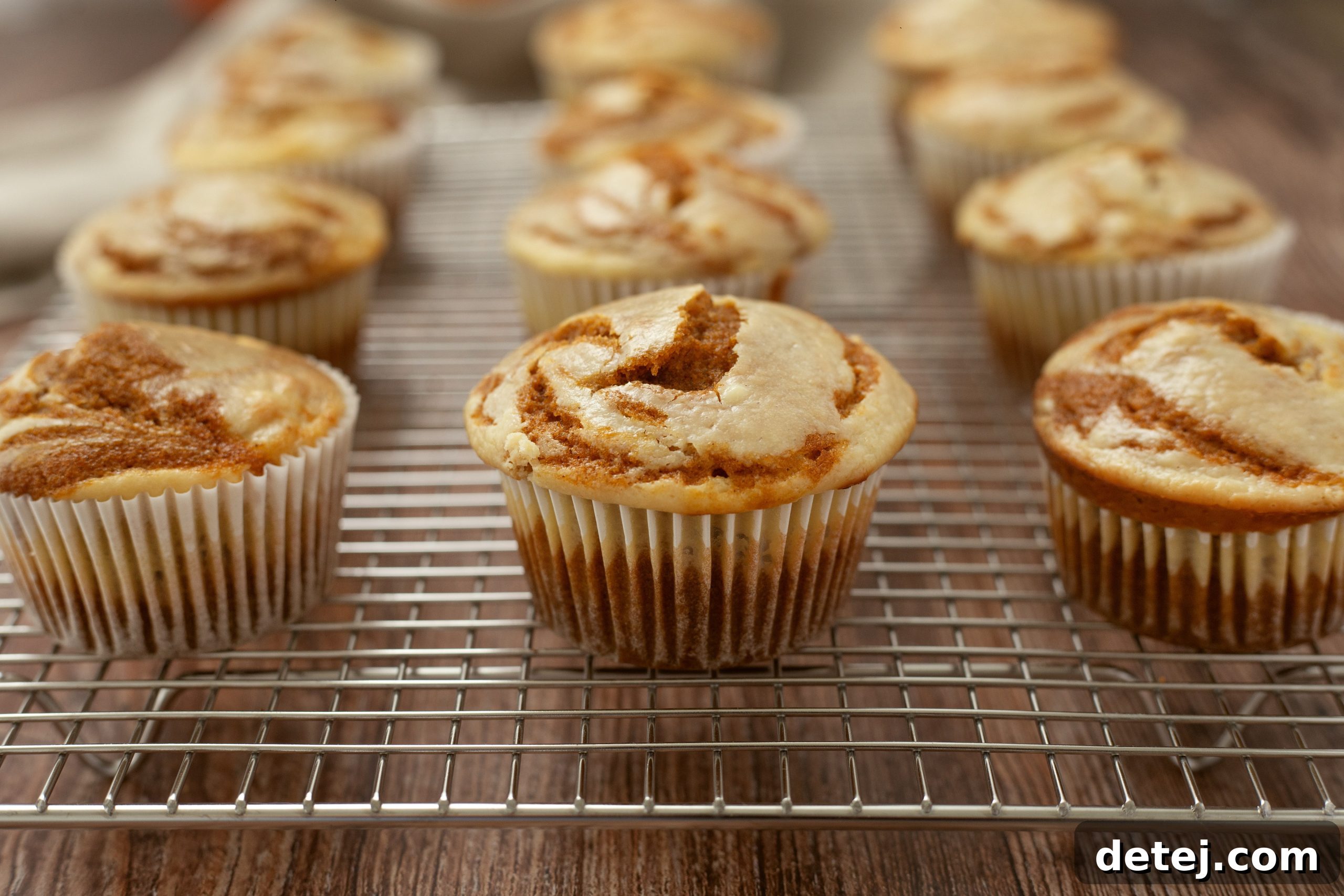 A close-up of a pumpkin cheesecake swirl muffin showing the distinct layers of pumpkin batter and cream cheese filling.