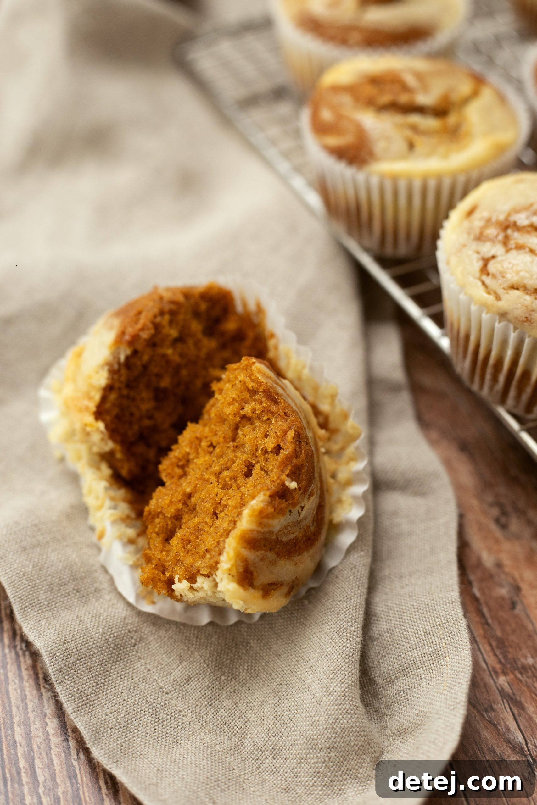 Freshly baked pumpkin cheesecake swirl muffins stacked in an airtight container for storage.
