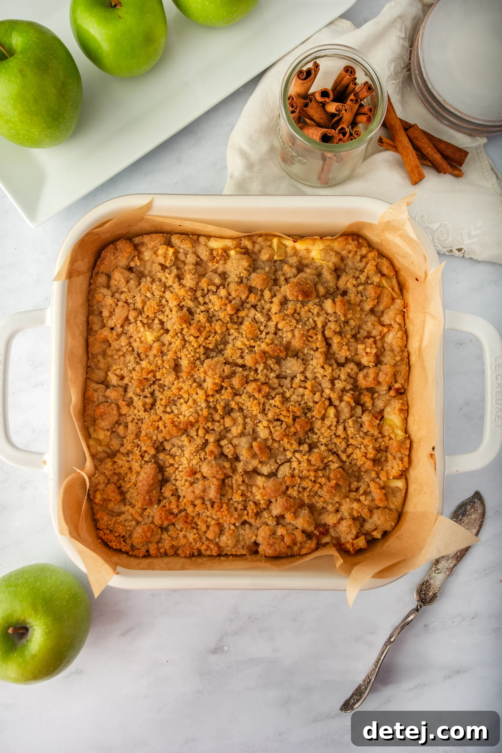 Freshly baked Apple Cheesecake Bars in a baking pan, showing the golden-brown streusel topping and set layers.