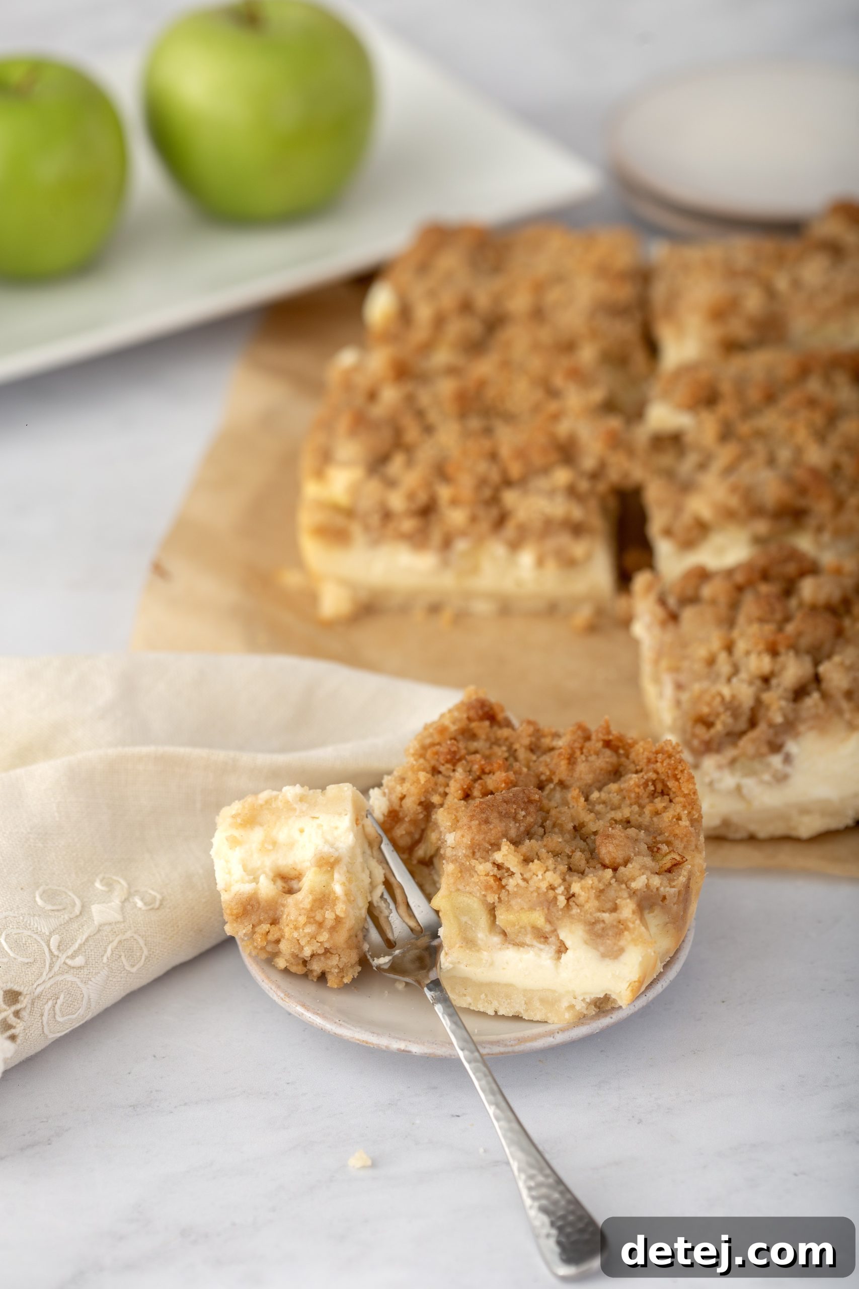 Perfectly sliced Apple Cheesecake Bars garnished with a drizzle of caramel sauce and fresh apple slices.