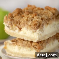 Finished Apple Cheesecake Bars, sliced and ready to serve, showing layers of crust, cheesecake, and apples.