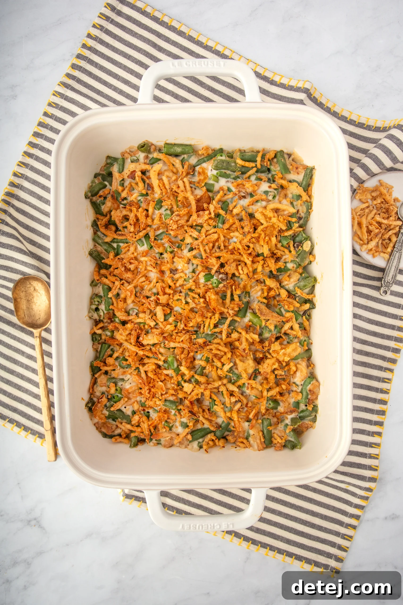 Green bean casserole baking in a glass dish, showing bubbly edges and a smooth surface before adding onions.