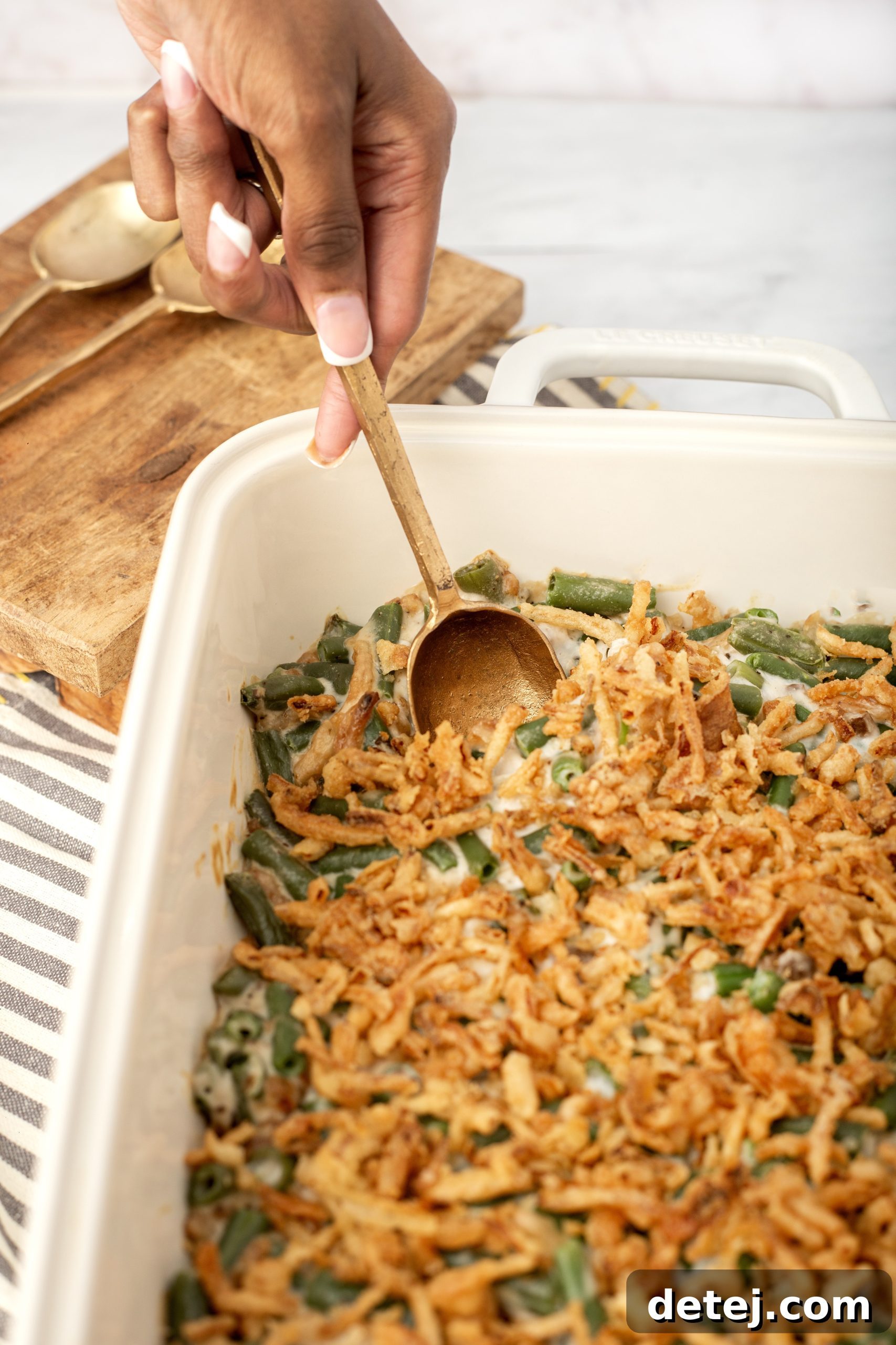 A finished green bean casserole, fresh out of the oven, resting on a trivet.