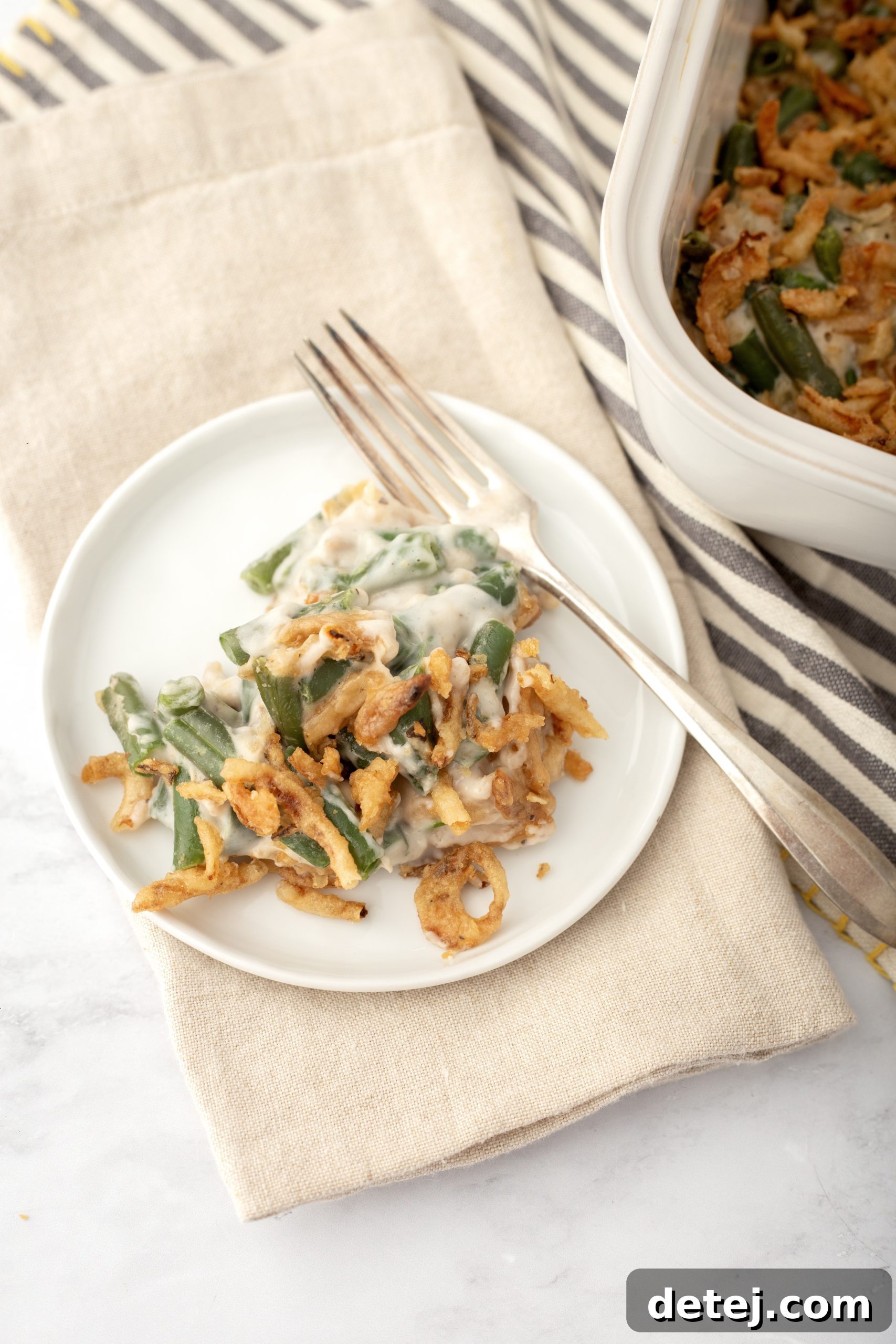 A slice of green bean casserole on a plate, garnished and ready to be served.