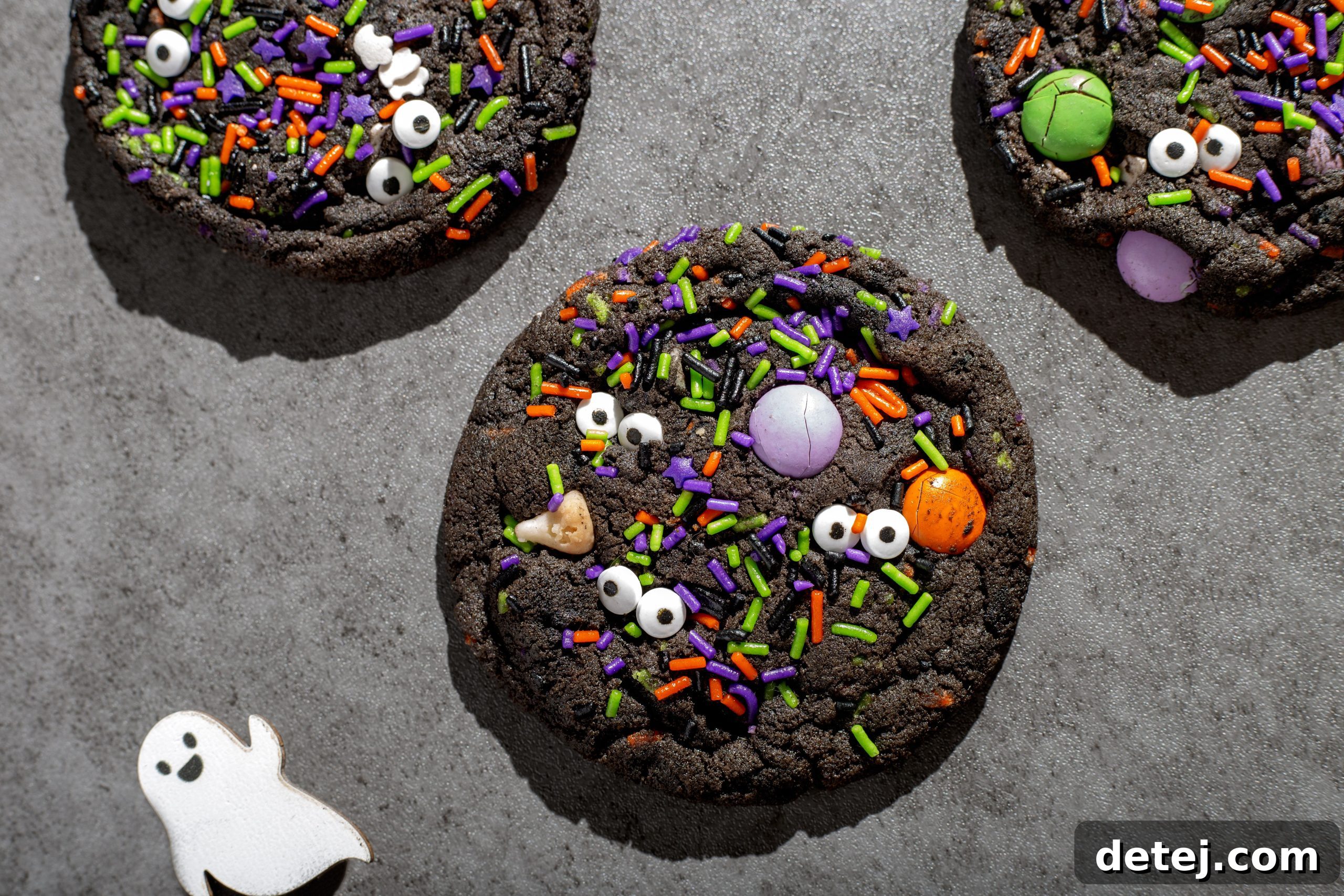 Frightfully Delicious Halloween Monster Cookies 3 Freshly baked Halloween Chocolate Monster Cookies cooling on a baking sheet, decorated with candy eyeballs and sprinkles