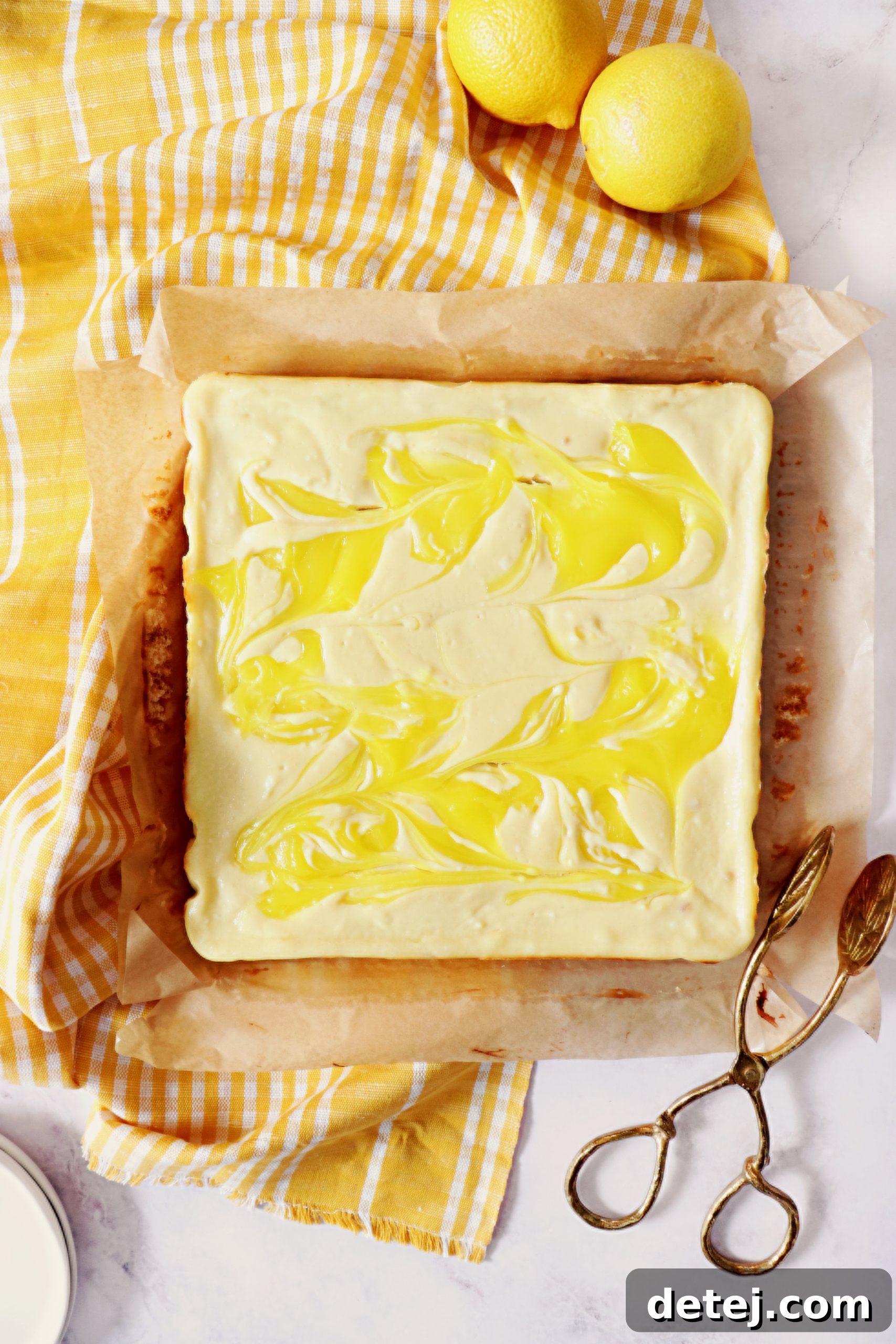 A close-up of cheesecake batter with lemon pie filling being swirled in with a knife, creating a beautiful marbled effect.