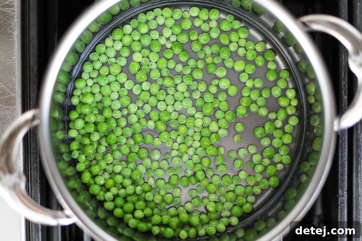 Fresh green peas being added to a pot of boiling water for blanching.