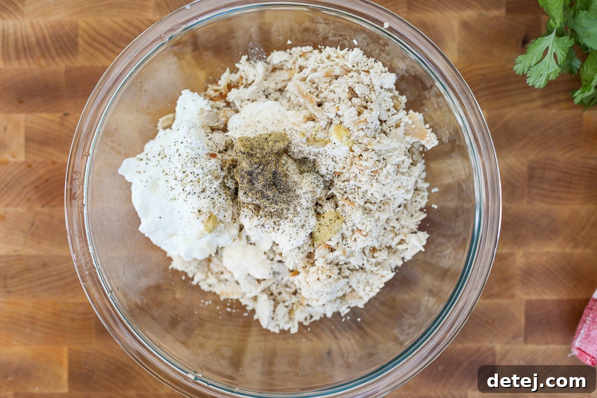 Shredded chicken and creamy dressing being mixed in a bowl.