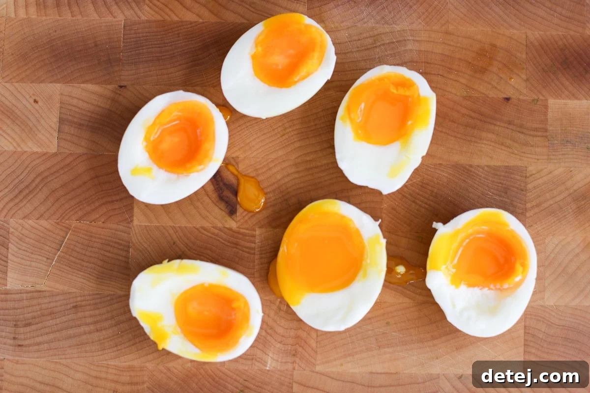 Perfectly boiled eggs, sliced in half, revealing their jammy yolks, ready for the cheese crust.