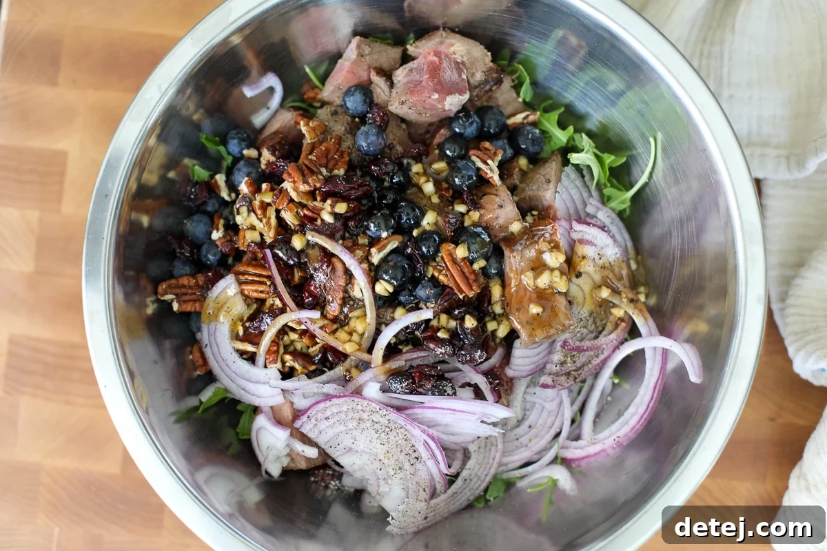 Seared Steak & Blueberry Harvest Salad 7 everything in a bowl with dressing.