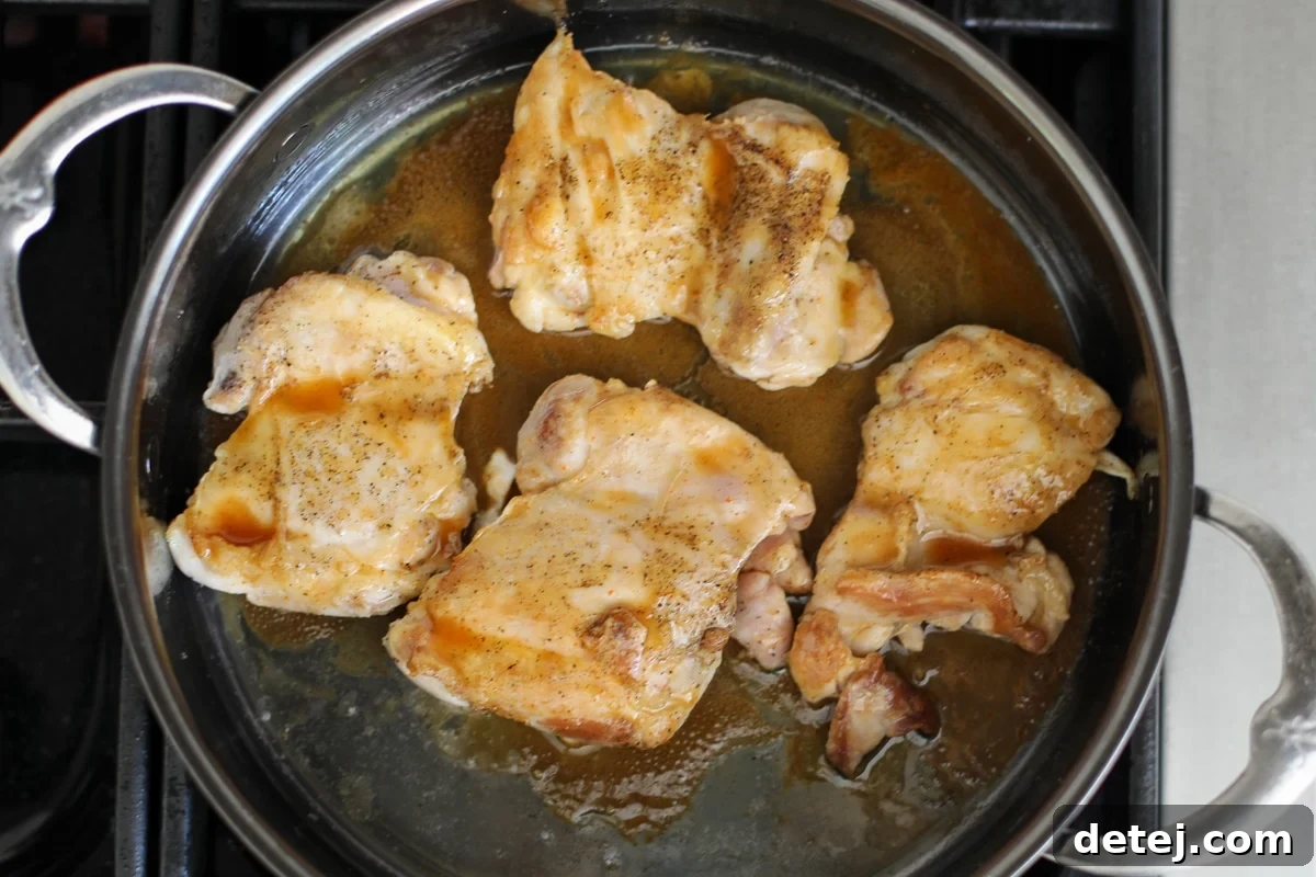 Sweet and Spicy Chicken Bowls with Sticky Glaze 6 chicken thighs in a pan with glaze.