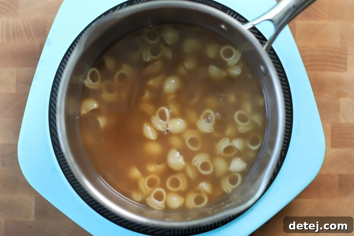 Bone Broth Pasta Recipe with Garlic, Herbs, and Parmesan 4 shellbows boiling.